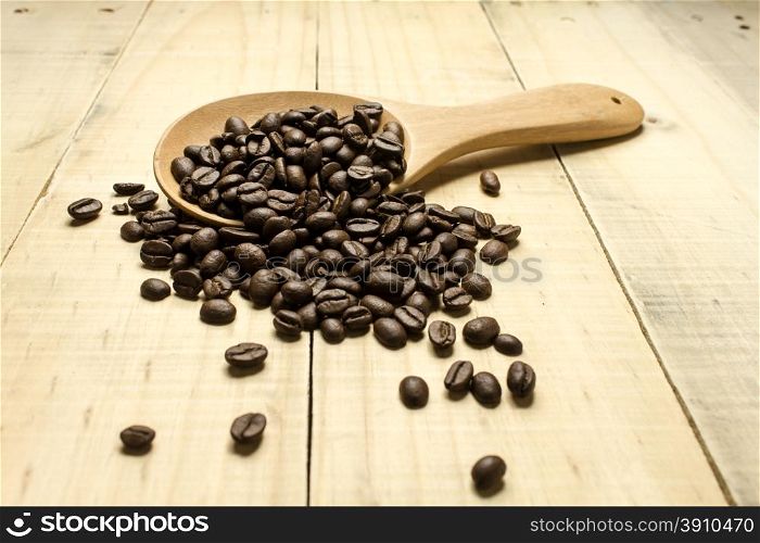 Coffee crop beans on spoon and wooden background
