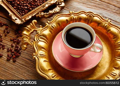 Coffee cup and beans on vintage golden tray in wooden old table