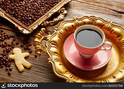 Coffee cup and beans on vintage golden tray in wooden old table