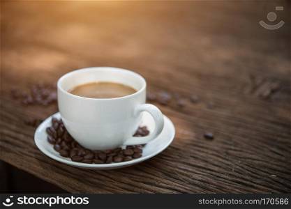 Coffee cup and coffee beans on wooden table.