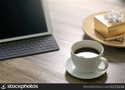 Coffee cup and Digital table dock smart keyboard,gold gift box and round wood tray,color pencil on wooden table,filter effect