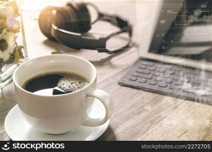Coffee cup and Digital table dock smart keyboard,vase flower herbs,music headphone,eyeglasses on wooden table,filter effect,icons screen