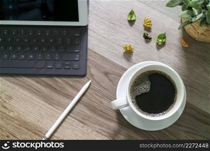 Coffee cup and Digital table dock smart keyboard,vase flower herbs,stylus pen on wooden table,filter effect