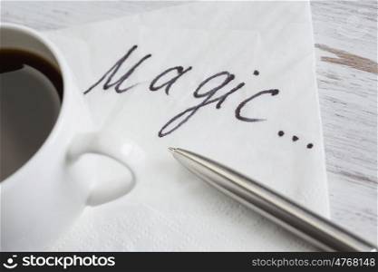 Coffee cup and napkin with message. Magic day message written on napkin on wooden table