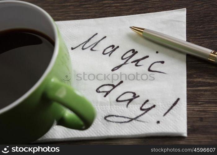 Coffee cup and napkin with message. Magic message written on napkin on wooden table