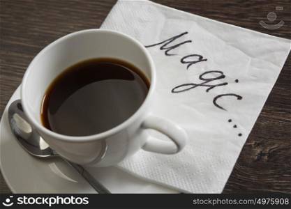 Coffee cup and napkin with message. Magic message written on napkin on wooden table