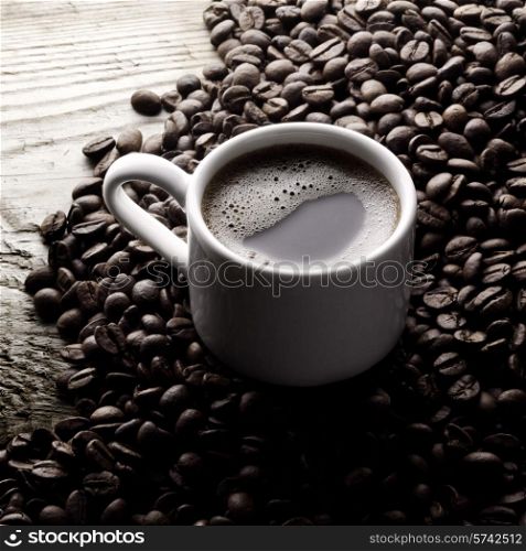Coffee cup and roasted beans on wooden table