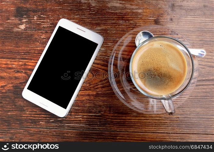 Coffee cup and smartphone on wooden office desk table.. Business work place