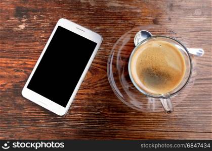 Coffee cup and smartphone on wooden office desk table.. Business work place