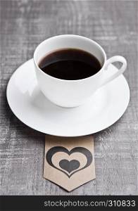Coffee cup hot white on wooden board with heart label. Grey wood