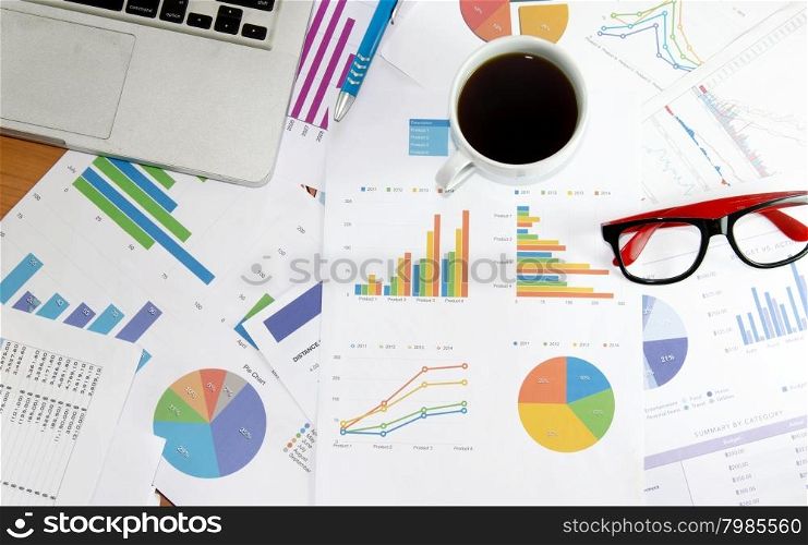 Coffee cup on financial papers, computer and office supplies