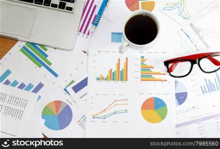 Coffee cup on financial papers, computer and office supplies