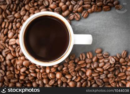 coffee cup on roasted coffee beans on the dark background top view