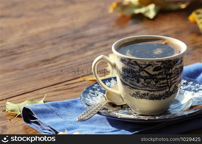 coffee cup on the autumn fall leaves and wooden surface background