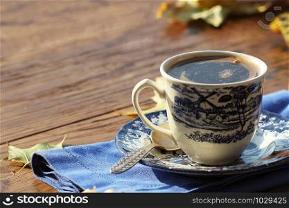 coffee cup on the autumn fall leaves and wooden surface background