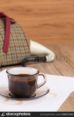 Coffee cup, paper sheets and detective hat on old Wooden table.