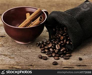 Coffee cup with burlap sack of roasted beans on a rustic table