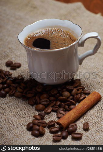 Coffee cup with cinnamon and coffee beans background