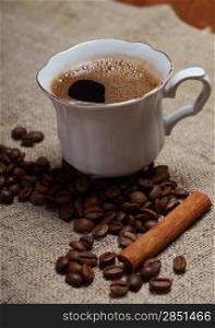 Coffee cup with cinnamon and coffee beans background