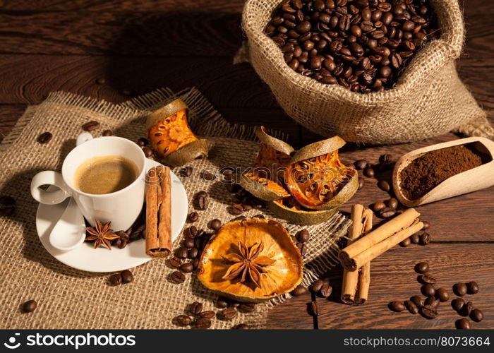 Coffee cup with cinnamon, star anise, dried orange fruit and coffee sack seen from above