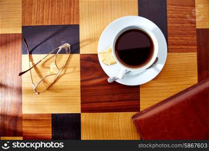 Coffee cup with glasses and leather folder on table retro vintage
