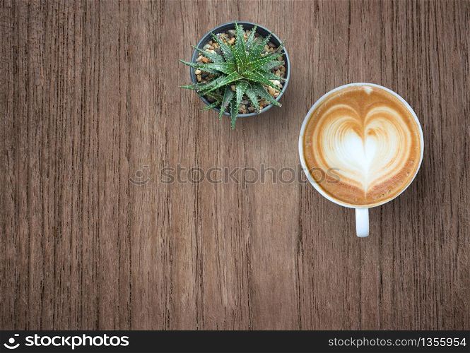 Coffee cup with plant top view on old wooden background