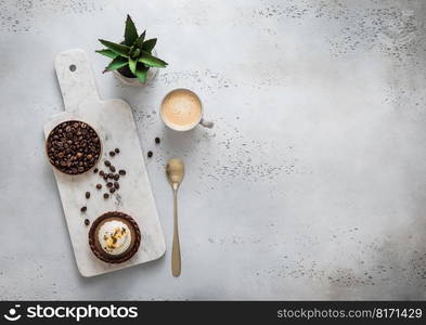 Coffee cup with raw beans and golden spoon and caramel dessert on marble board.Top view.