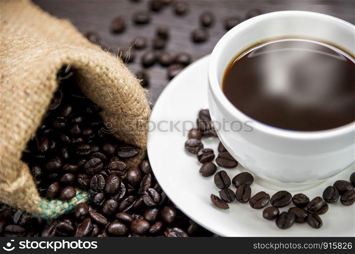Coffee cup with smoke and coffee beans in sack on wood table, Drinks and relax concept, for advertising