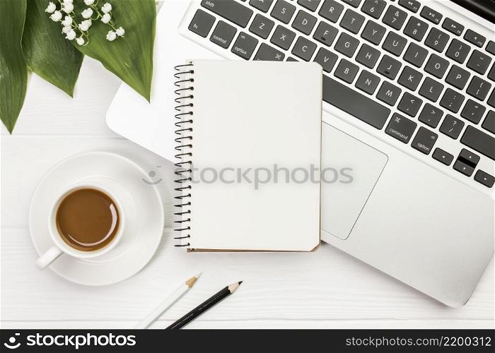 coffee cup with spiral notepad laptop with colored pencils office wooden desk