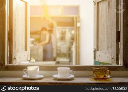 Coffee cups on opened grunge wooden window pane with outdoor view