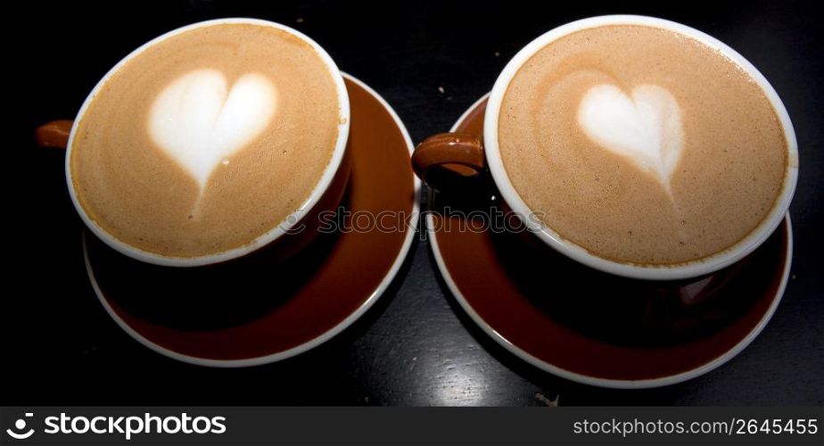 Coffee cups with heart shaped cream, close-up
