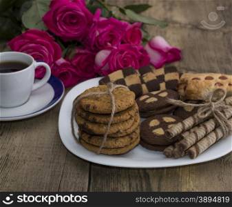 coffee, flowers pink and different cookies on a plate