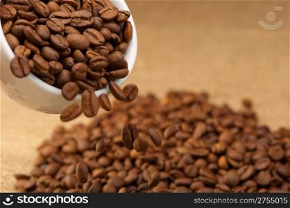 Coffee grains fall from a cup. Photo closeup