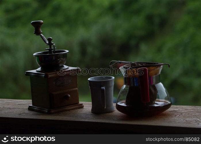 Coffee grinder with black coffee on wooden and nature background