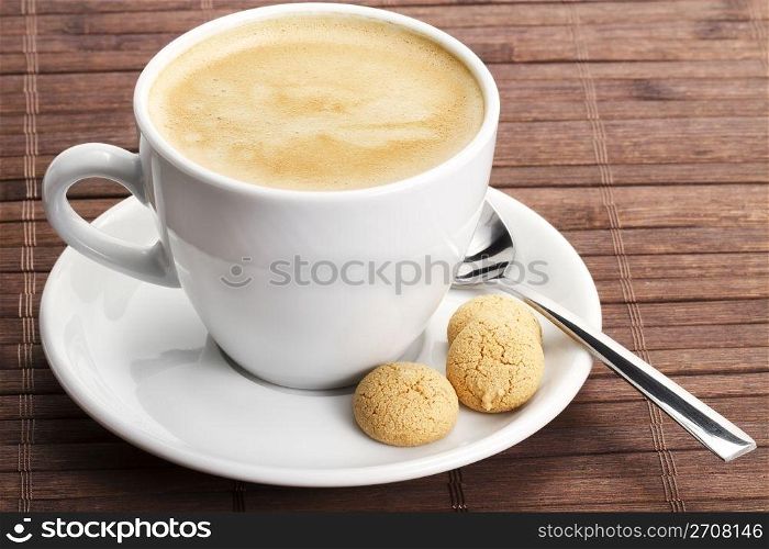 coffee in a white cup with amarettini and spoon. coffee in a white cup with amarettini and a spoon on wooden background