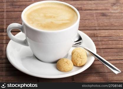 coffee in a white cup with amarettini and spoon. coffee in a white cup with amarettini and a spoon on wooden background
