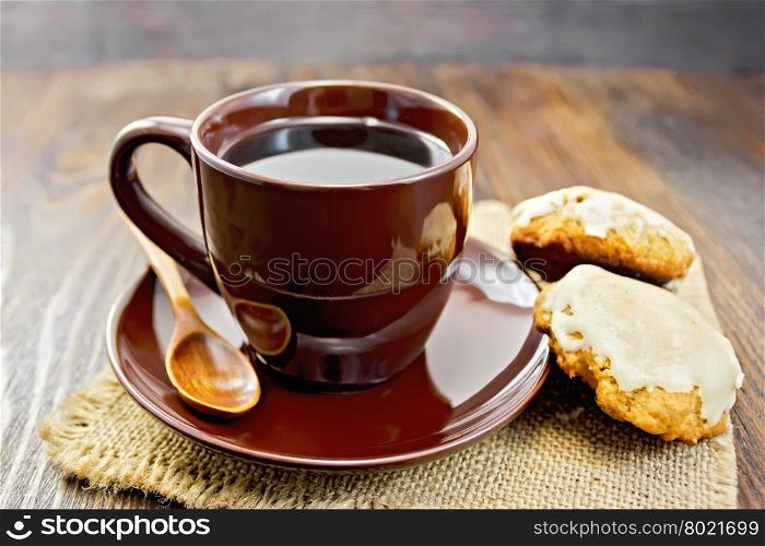 Coffee in brown cup with biscuits pumpkin on a napkin from a sacking on a background of wooden boards