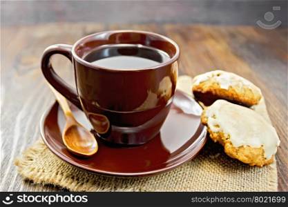 Coffee in brown cup with biscuits pumpkin on a napkin from a sacking on a background of wooden boards