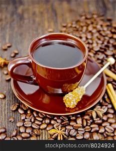 Coffee in cup brown with sugar, coffee beans, cinnamon sticks and star anise on a wooden boards background
