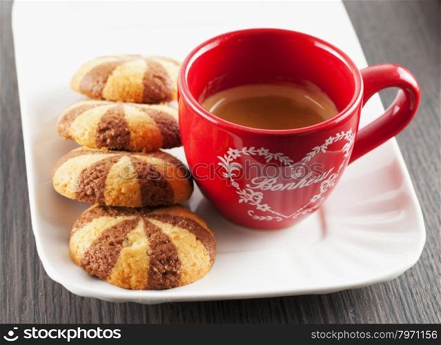 Coffee in red cup with biscuits over white plate, horizontal image