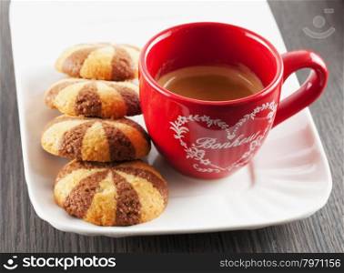 Coffee in red cup with biscuits over white plate, horizontal image