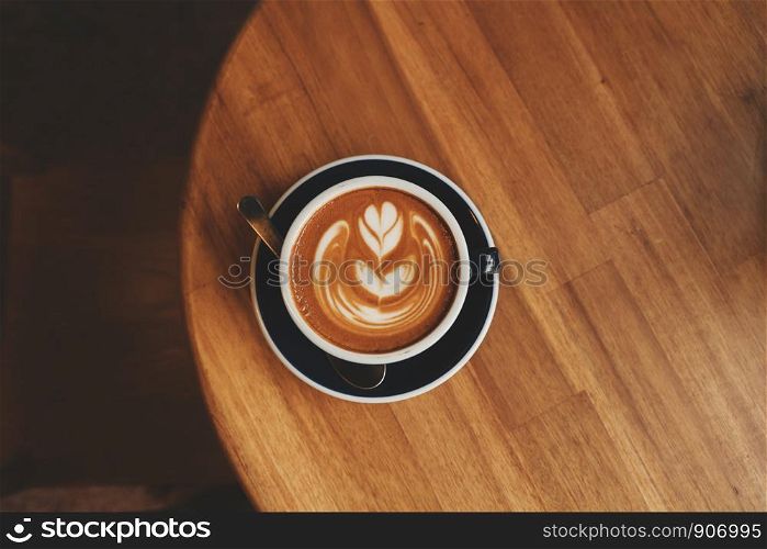 coffee latte art on the wood desk in coffee shop cafe in vintage color tone