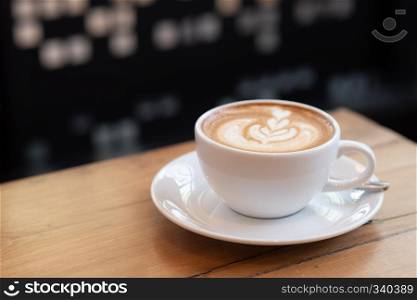 coffee latte in a white cup on wooden table in coffee shop.