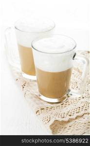 Coffee latte in glass mugs on white table