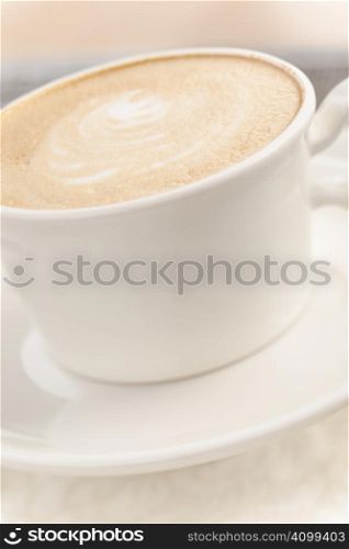 Coffee (latte) with milk foam on light brown table