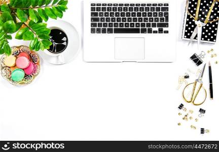 Coffee, macaroon cookies, office supplies, laptop computer and green plant on white table background. Business still life
