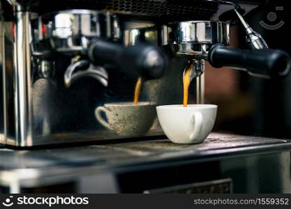 coffee machine mixing espresso shot in glass cup on the plate in coffee shop