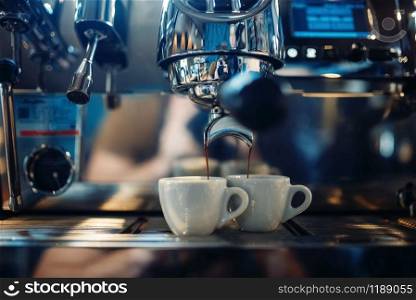 Coffee machine pours fresh espresso into the cups closeup, nobody. Professional restaurant, cafe or cafeteria business tools. Coffee machine pours fresh espresso into the cups