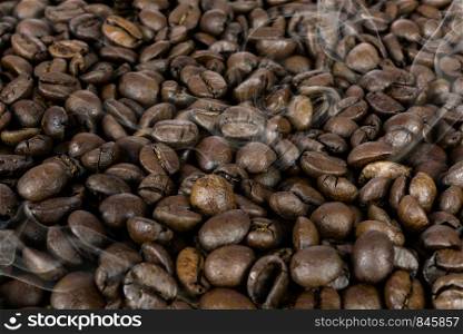 Coffee production background - many hot roasted brown beans and smoke in close-up as a texture (high details).