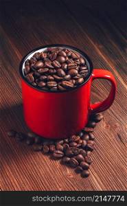 Coffee red mug with beans on wooden background. Coffee red mug with beans